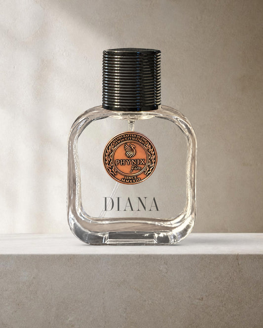 DIANA 50 mL Parfum by Phynix Fire Studios — clear glass bottle with copper coin seal, warm ivory plaster with soft diagonal daylight on a pale stone ledge