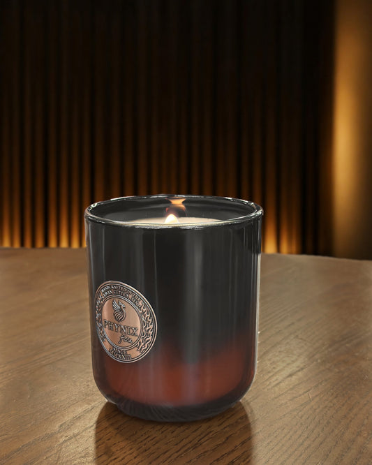 NOX OUD Luxury Candle in the PARVUS 8 oz vessel, lit, on a walnut table
