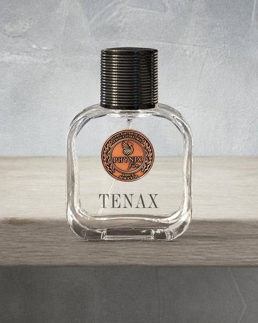 TENAX 50 mL Parfum by Phynix Fire Studios — clear glass bottle with copper coin seal, weathered grey-blue limewash on bleached oak